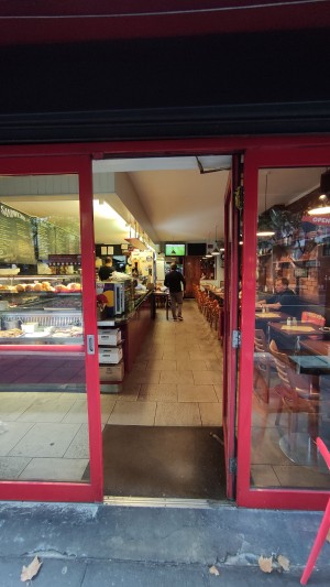 Glass door with red frames ahead. Push red door handle to left.