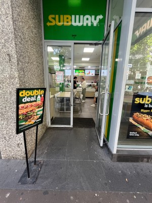 Glass double doors with grey metal frame. Pull from middle. Signage obstructing on left.