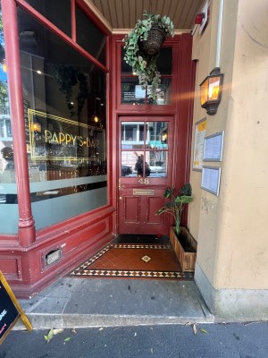 Path to entrance from street. Red wooden door with glass panels directly ahead. Turn handle and push from left.