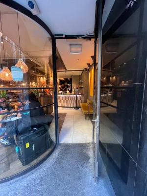 Glass door with black metal frame. Turn handle and pull from left to open.