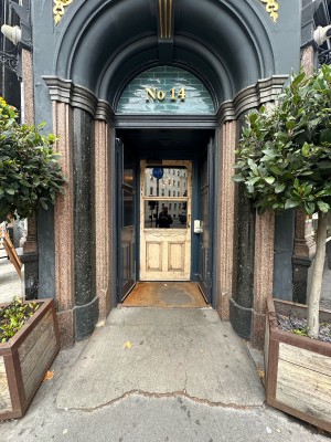 First set of blue doors. Push from centre to open. Planters to left and right of doors.