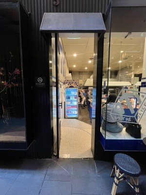 Glass door with black metal frame. Push from right. Two steps down to main area on right through door.