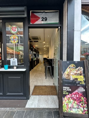 Glass door with black frame. Silver metal vertical handle on left, push to open. A-frame to right of door.