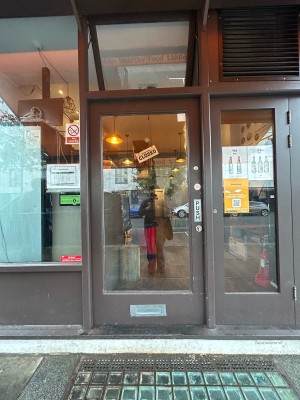 Single glass door with brown frame. Push from right to open.