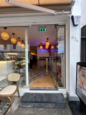 Glass door. Silver metal vertical handle on left, push to open. Standing sign on right. Seating on left.