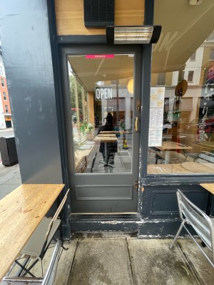 Glass door with grey wooden frame ahead. Gold metal handle to right. Push to open.
