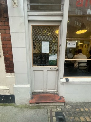 White wooden and glass door ahead. Silver metal handle to right. Push to open.