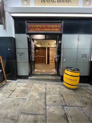 Path ahead, going straight. Two steps up before doors. Black double doors ahead. Pull silver handles at centre to open.
