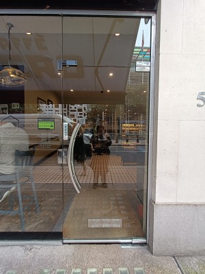 Glass door with silver, curved, metal handle on left. Push to open.