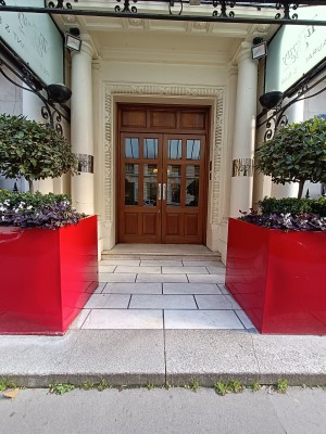 From street, facing venue. Planters on both sides. Steps up to doorway at back. Path ahead.