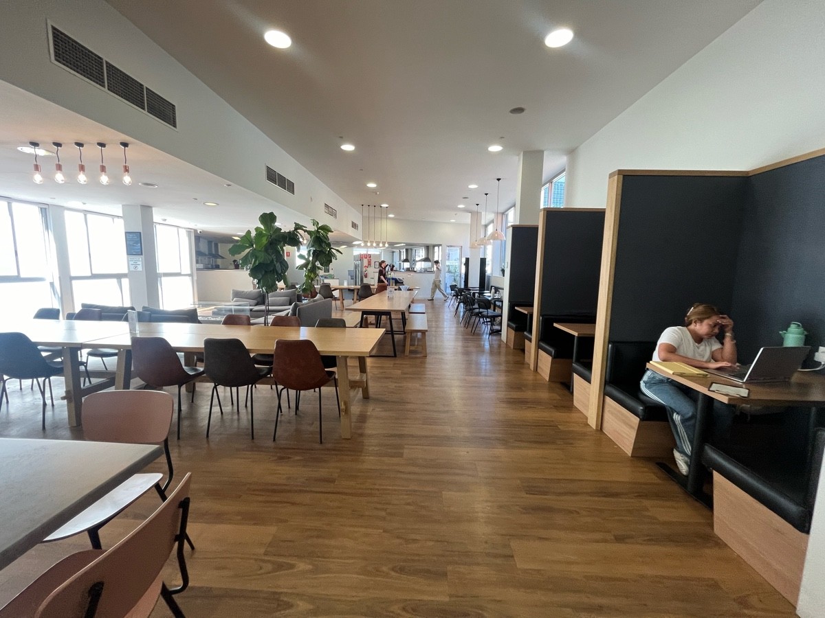 From path after shifting right. More tables and chairs on left followed by tables and benches, and couches further left. Path shifts right again.
