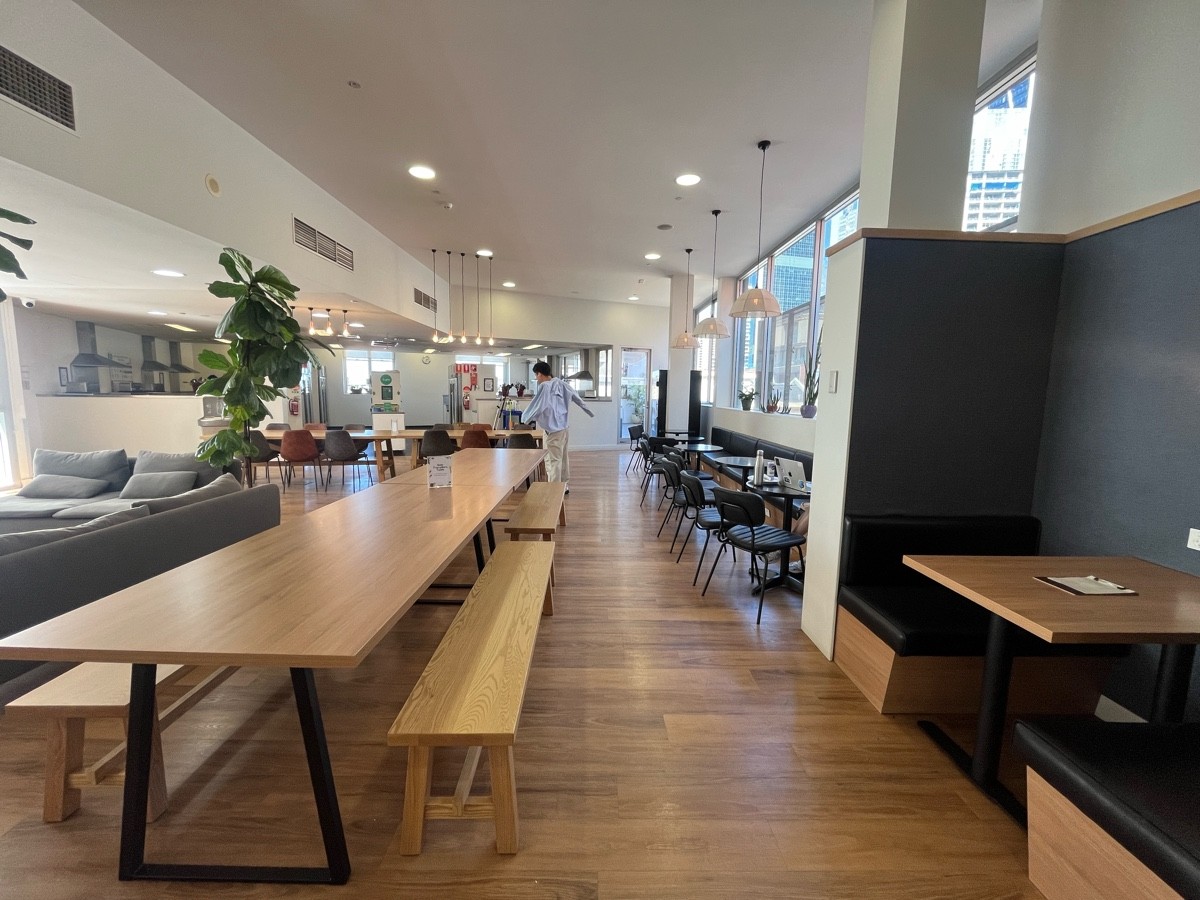 From path after shifting right again. Tables and benches on left, couches further left. Half booths along right wall after booths.