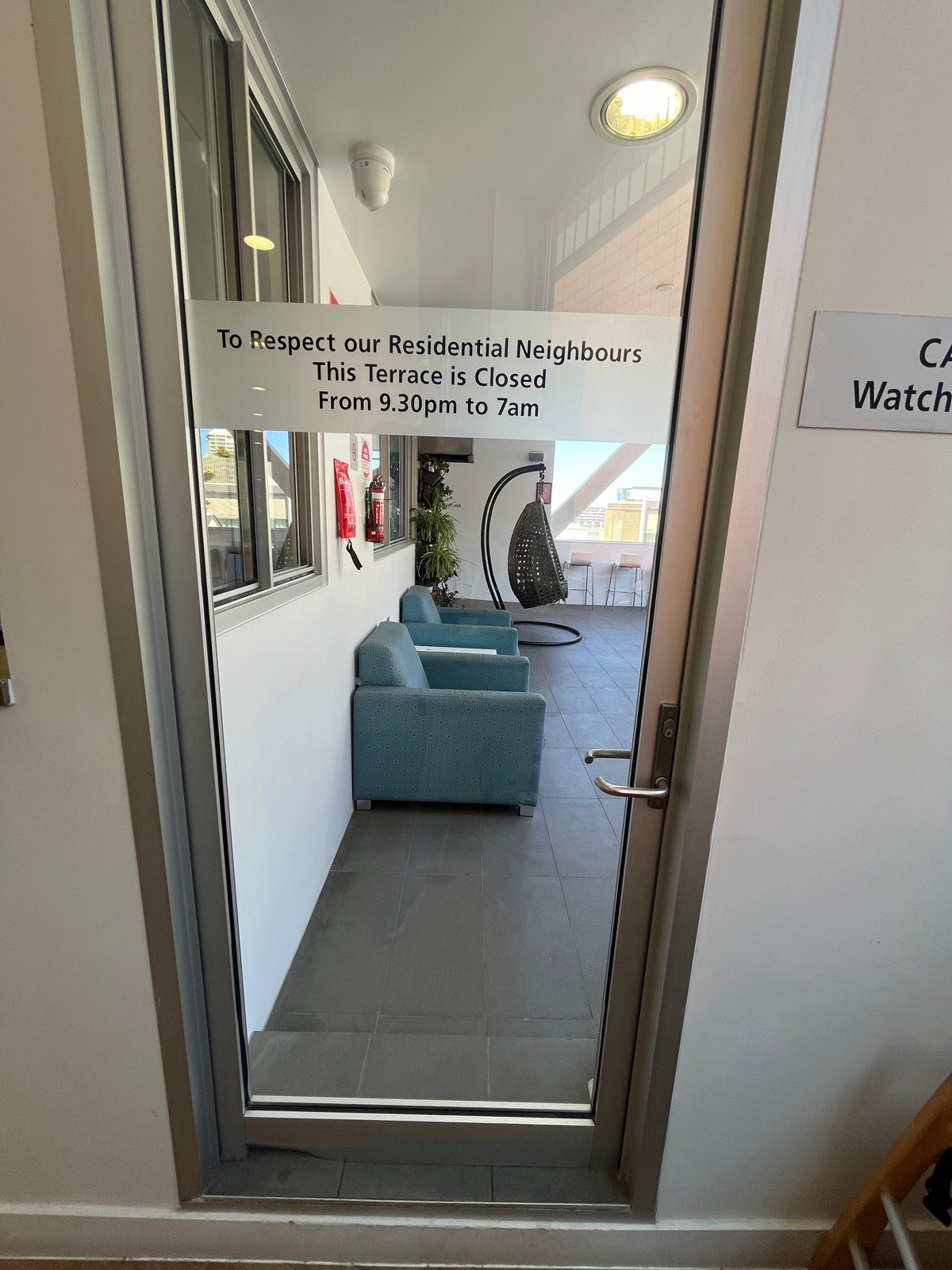 Glass door with silver metal frame. Turn handle and push from right. One step up through door.
