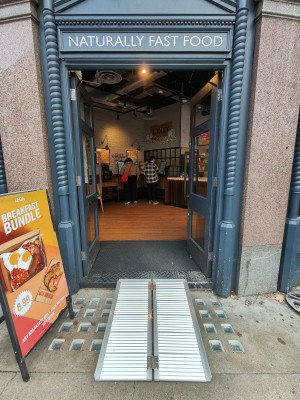 Facing grey-framed double glass doors. Push black metal vertical handles in centre to open.