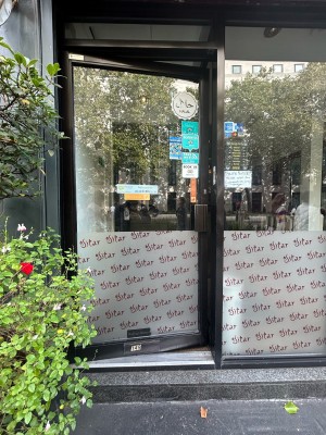 Single glass preceding door with black metal frame and square black metal handle on right. Push to open.