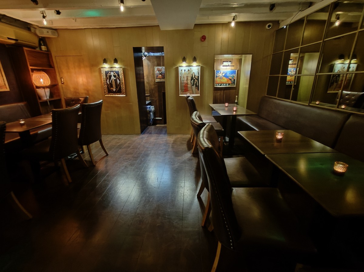 From bottom of stairs facing left. Half booth ahead. Straight path on left. Half booths along far left wall.