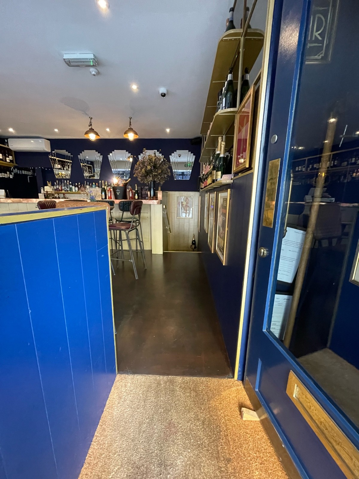 From door, facing straight. Blue wood-panelled divider on left. Path ahead.