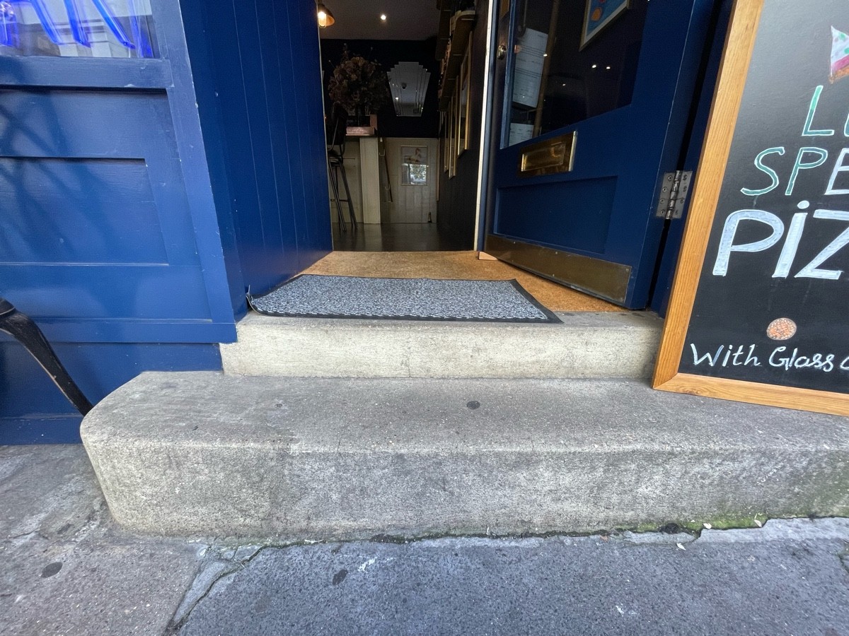 Two stone steps up before door. A-board on right of first step. Doormat immediately after door.