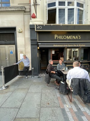 Path ahead, going straight. Outdoor seating on right. Door at end of path.