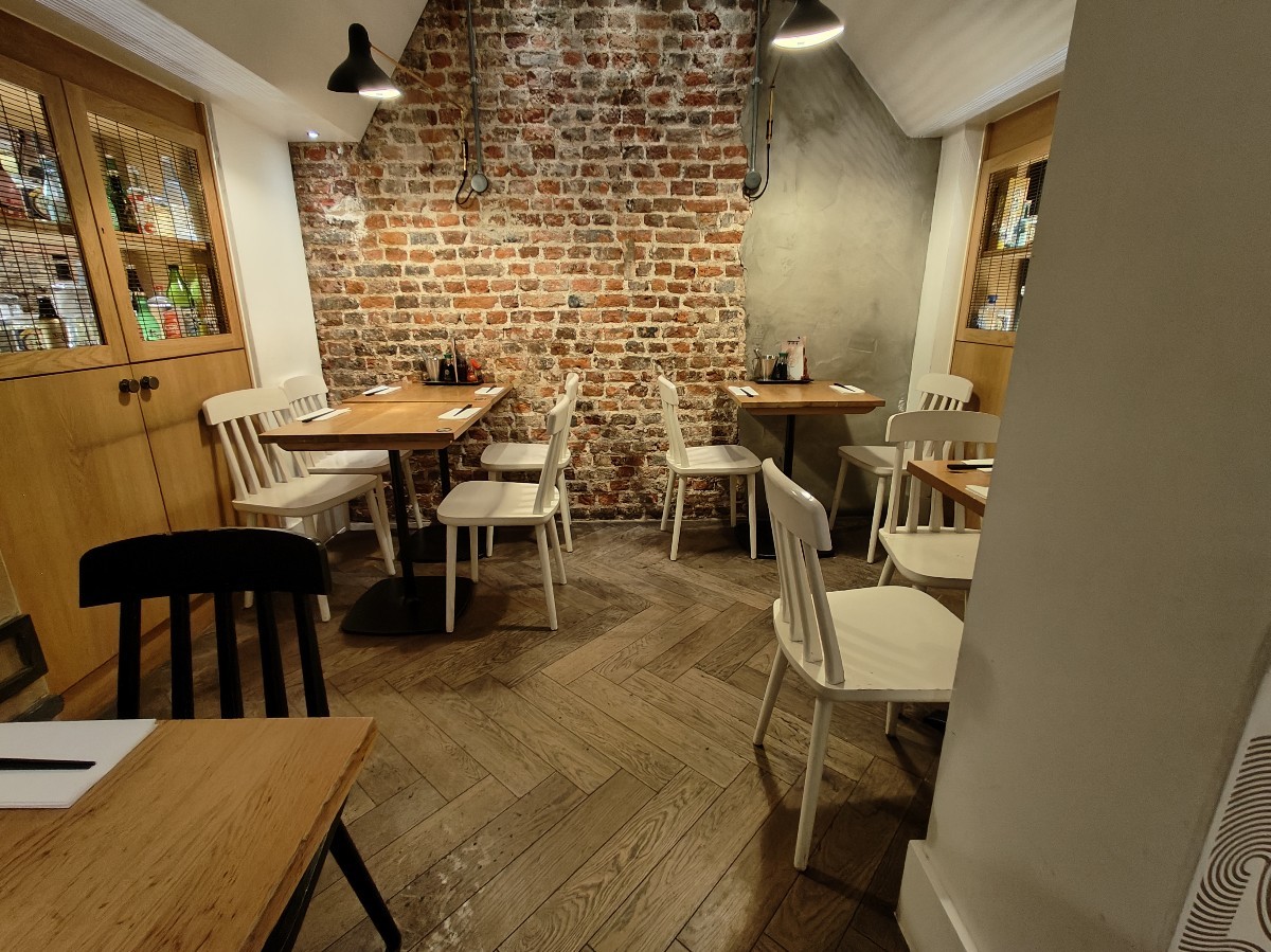 From archway at end of front area seating facing right. Tables and chairs on left and right. Straight path ahead.