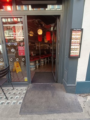Glass door with black frame. Silver, metal turn handle on left. Push to open.