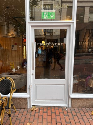 Single glass door in white wood frame. Push silver metal panel on the left.
