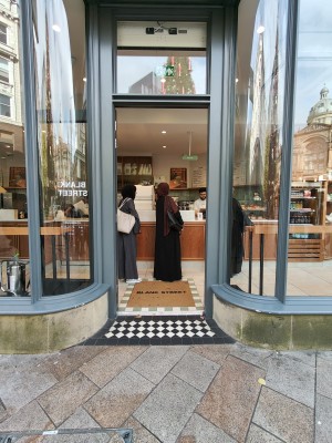 Facing grey framed single glass entrance door. Push silver vertical handle on right to open.