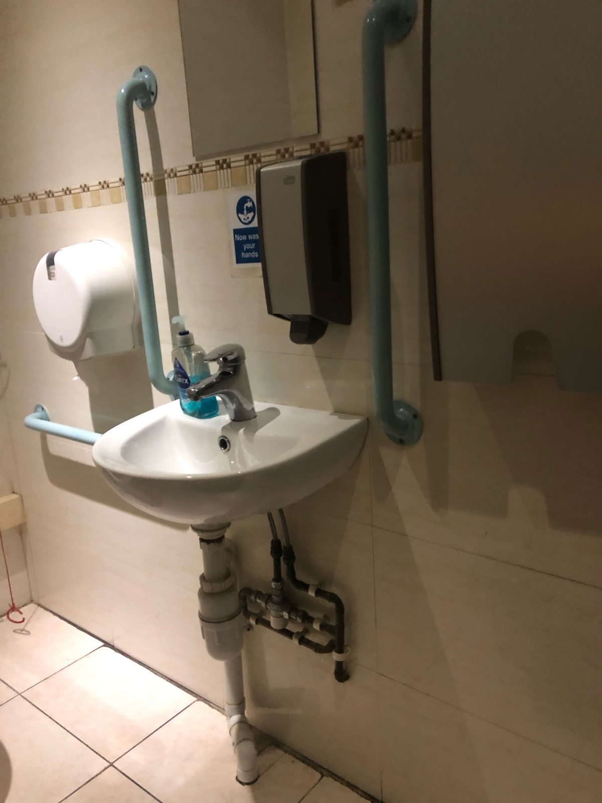 Bathroom sink on the right wall and soap dispenser