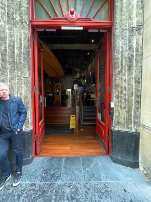 Glass double doors with red wooden frames. Push from middle.