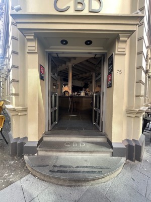 Glass double doors with grey metal frames. Push from middle. 3 steps up to doors. Doormat after doors.