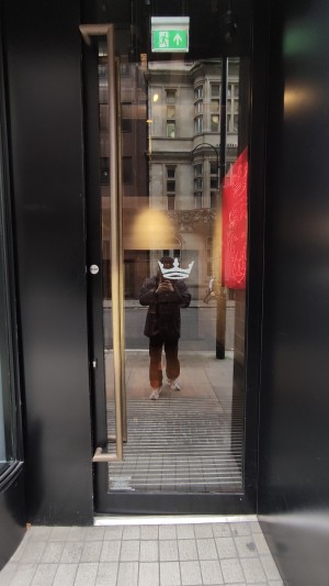 Glass door with black frames ahead. Push metal vertical handle to left to open.
