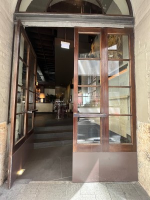 Glass doors with brown wooden frame. Push horizontal brass handles from middle to open.