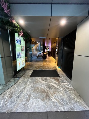Open archway from street leading to glass double doors. Push from middle. Doormat before door.