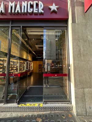 Glass doors with silver metal vertical handles in centre, push to open. White and black doorbell to right of doors.
