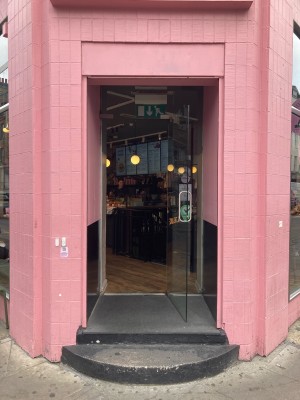 Access via glass door in a pink brick frame. Pull open via metal handle on left.