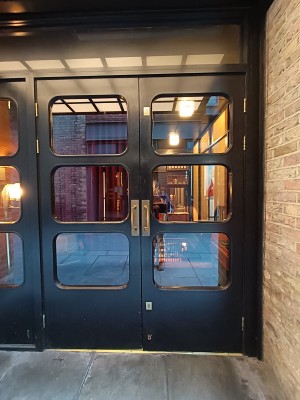 Glass doors with black frame. Golden, metal handles in middle. Pull to open.