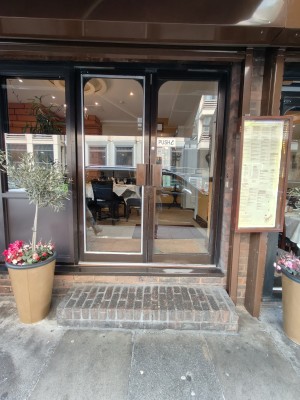 Facing brown framed double glass doors ahead. Push brown handles in centre to open.
