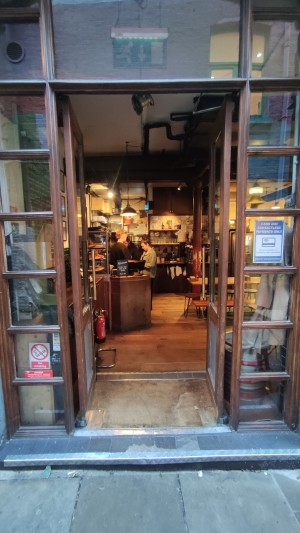 Glass doors with wooden frames ahead. Push brass vertical handles in centre to open.