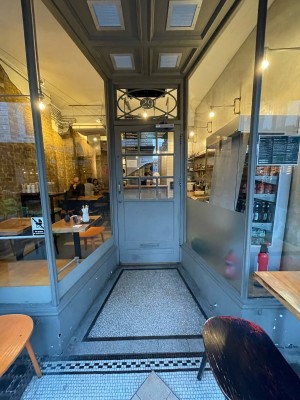 Opening with glass walls to left and right ahead. Glass and wooden blue door at back wall. Gold metal handle to left. Pull to open.sm