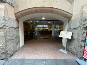Open archway from street to venue. Slight slope up to and through archway. Signage on right side of archway.