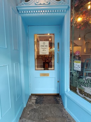 Glass door with blue frame. Golden, metal handle on right. Pull to open.