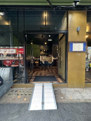 Glass doors with black frame. Black metal vertical handles in centre, push to open.