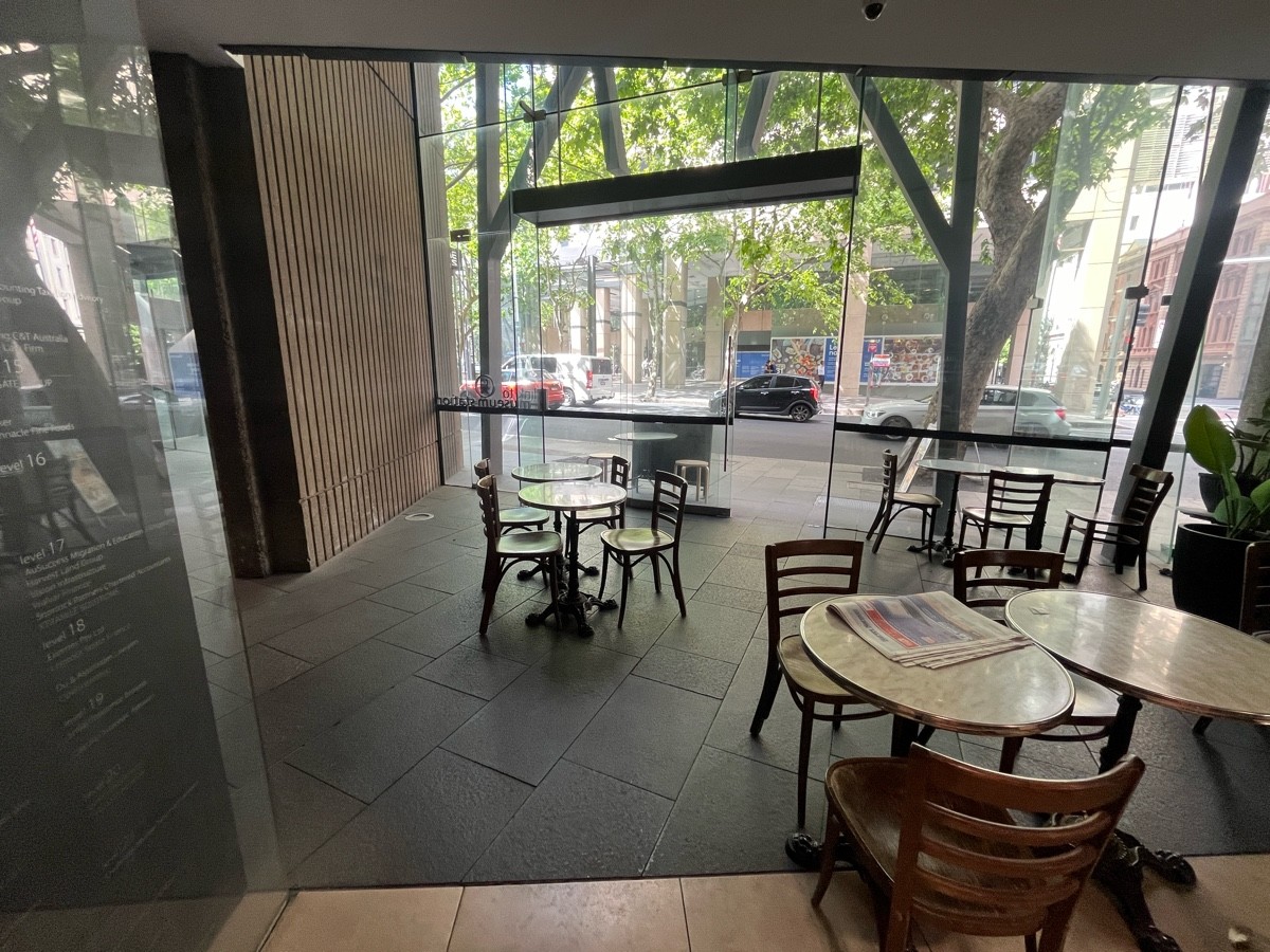 From after large table and archway facing straight. Tables and chairs ahead and to right. Door to outdoor side on wall ahead to right.