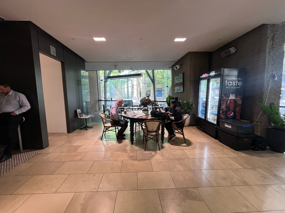 From midpoint of counter facing right. Large round table with chairs ahead. Archway to ramp on left wall. Path in between.