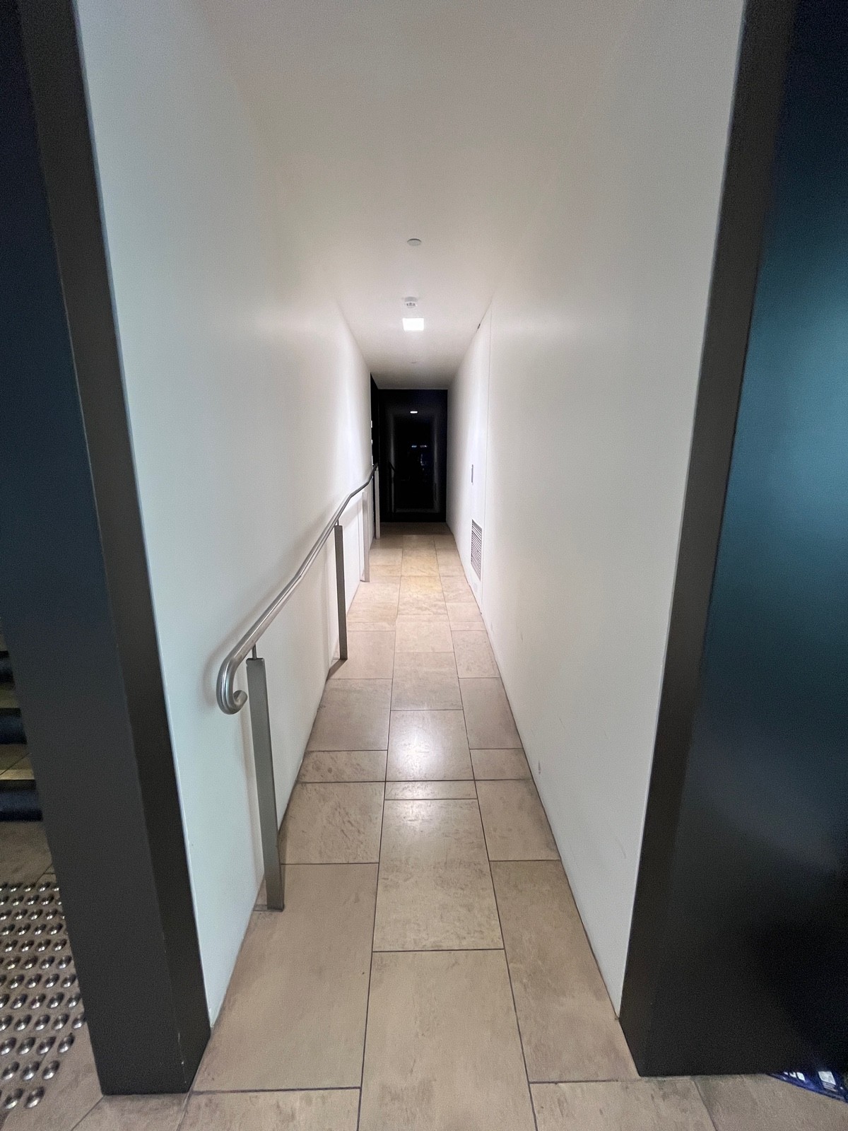 Open archway to right of steps. Built in ramp ahead through archway. Handrail on left.