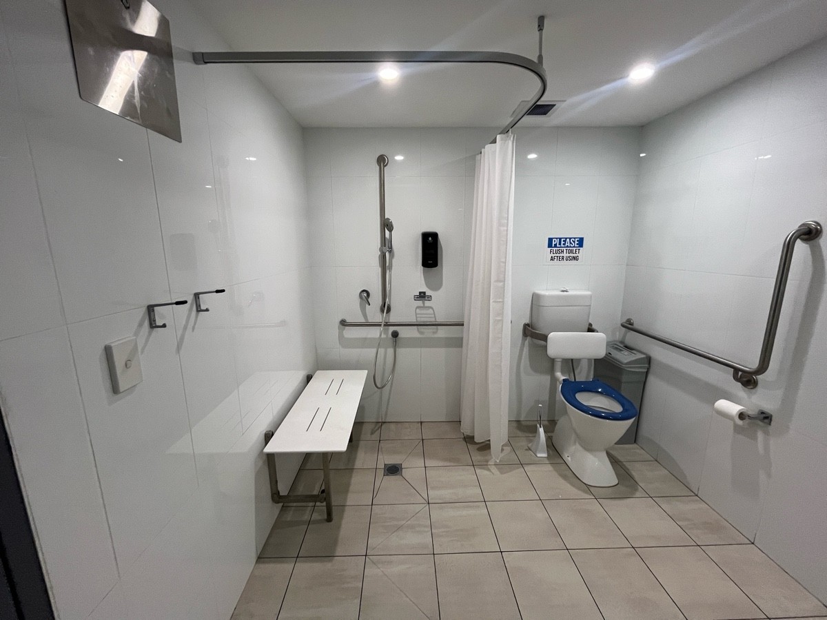 From door facing left. Shower bench on left wall. Shower on wall ahead. Toilet on wall ahead to
Right.