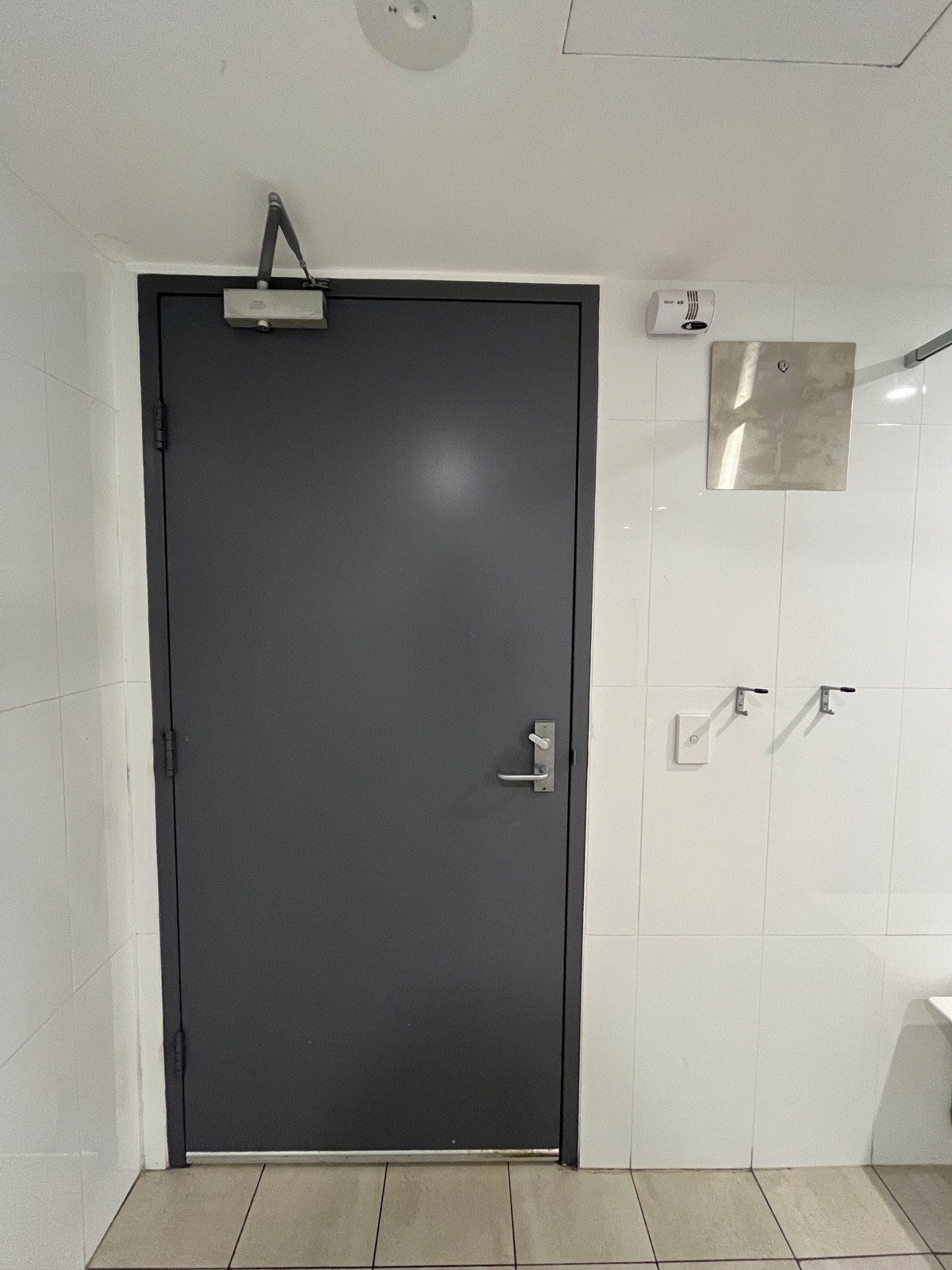 Back of door. Turn lock on right above handle. Light switch to right of door followed by seated height hooks.