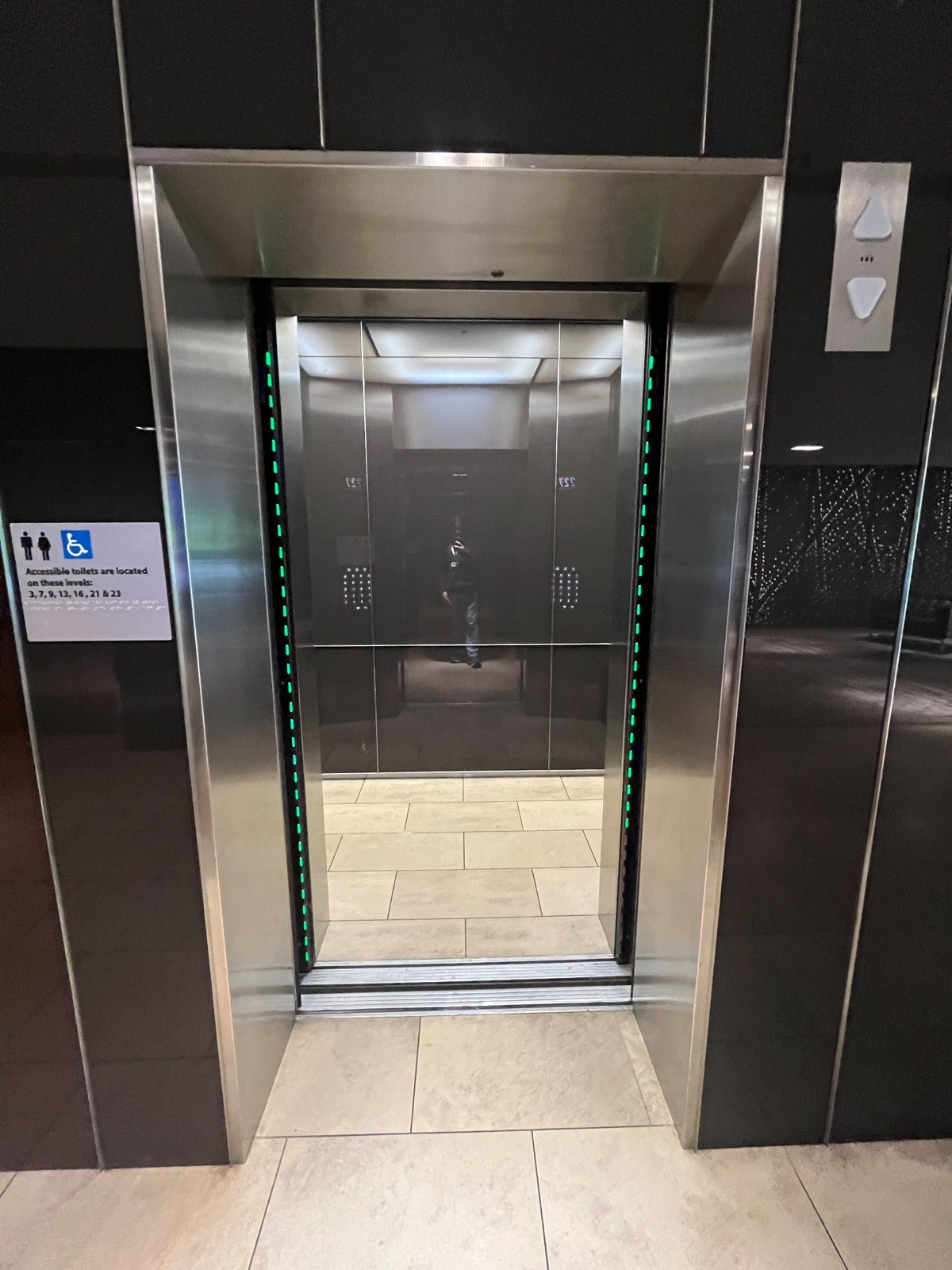 From hallway after upstairs seating facing left. Silver metal lift doors open from middle.