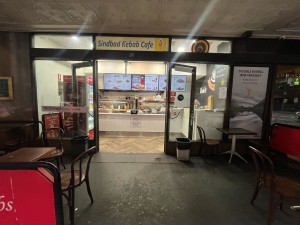 Path to entrance from street through outdoor front seating. Doors ahead to left.