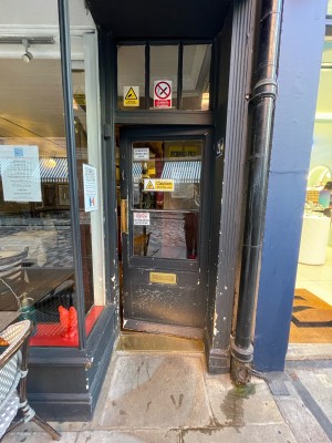 Black wood and glass door. Push golden pad on left to open.